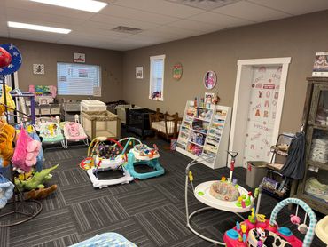 A cozy baby store corner with cribs, walkers, and toys.
