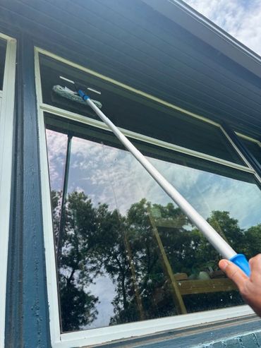 Person cleaning upper window frame with a mop.