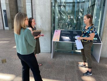 Three women chat in an airy-looking lobby.