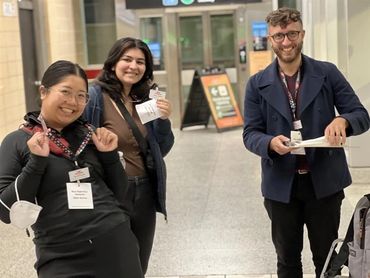 Three smiling LTRT staff wearing dark clothes and lanyards smile directly into the camera.