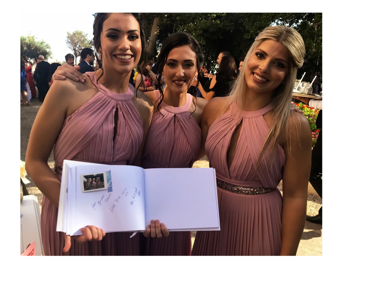 Bridesmaids filling out polaroid guestbook during wedding