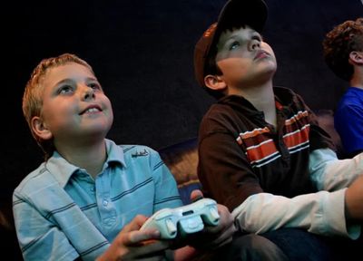 Two boys intensely playing video games with controllers in hand.