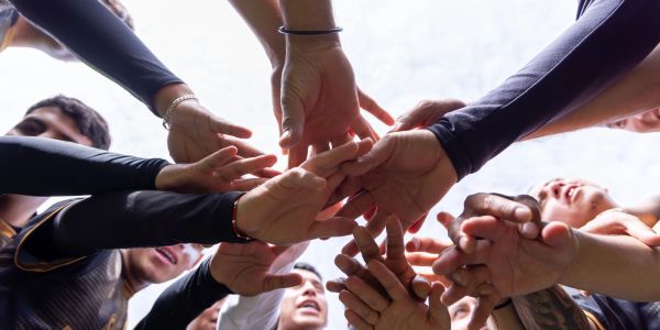 Team members joining hands in a circle for unity.