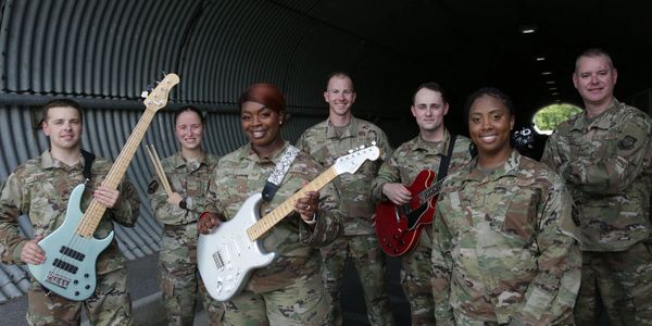 A diverse group of soldiers in uniform with musical instruments inside a tunnel.