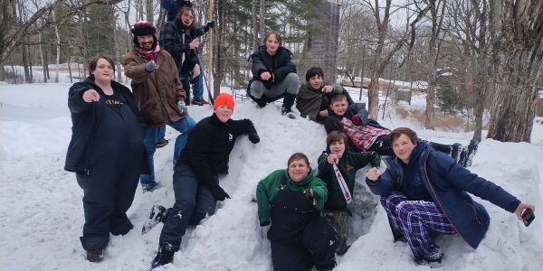 Group of kids posing on a snowy hill outdoors.