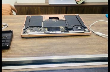 Opened laptop showing internal components on a wooden table.