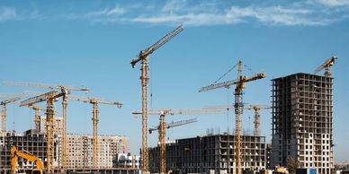 Multiple cranes working on high-rise building construction sites under a clear sky.