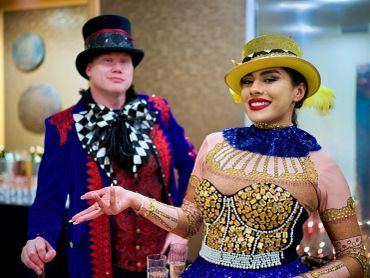 Two people in colorful, elaborate costumes with hats, smiling.