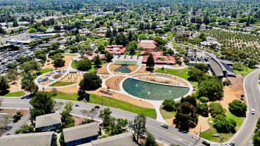 Aerial view of a park with buildings and a pond.