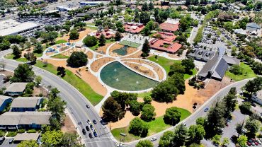 Aerial view of a park with ponds, pathways, and buildings.