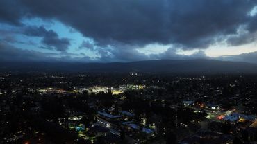 Cityscape at dusk with dark clouds and illuminated streets.