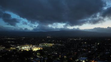 City lights under a cloudy evening sky.