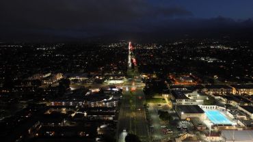 Night aerial view of city street with lights and buildings.
