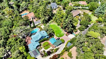 Aerial view of residential houses surrounded by lush green trees.