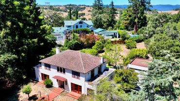 Residential homes surrounded by lush trees and hills.