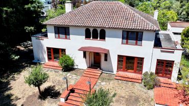 Two-story tile-roof house with red doors and windows.