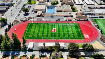 Aerial view of a sports field with track and pool.