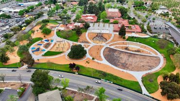 Aerial view of a park with pathways, playground, and buildings.