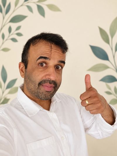 Jai Dhillon, creator of POPWAT, smiling and giving a thumbs-up against a cream and green leaf backgr