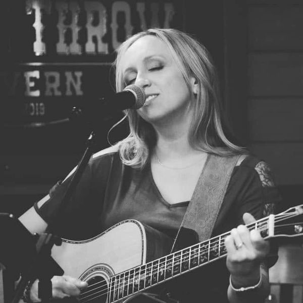 Woman singing and playing acoustic guitar.