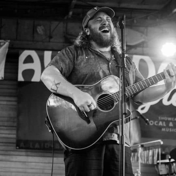 Man passionately singing and playing guitar on stage.