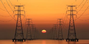 Power lines at sunset over calm water create a symmetrical view.