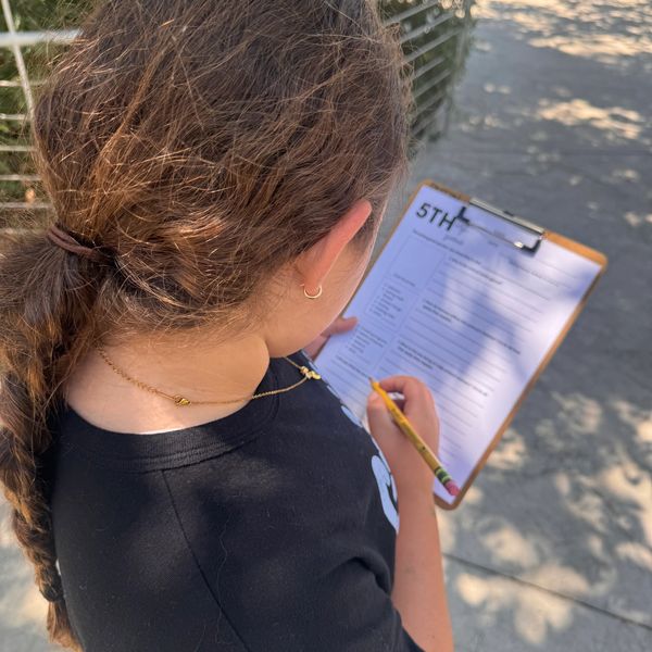 On the go learning child filling out observations on a clipboard