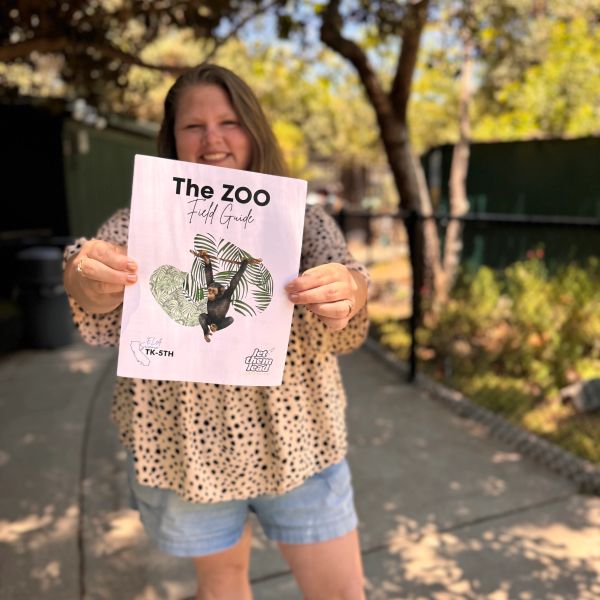 A woman holding a zoo field guide outdoors.