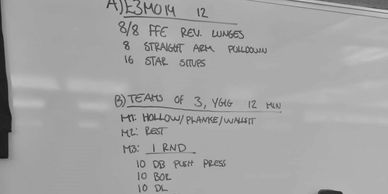 Whiteboard with detailed workout plan including exercises and repetitions.