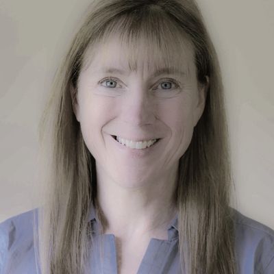 Smiling woman with long straight hair wearing a blue shirt.