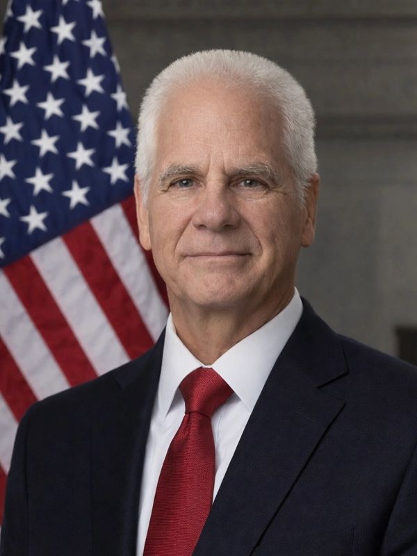 Portrait of a serious man in a suit with an American flag background.