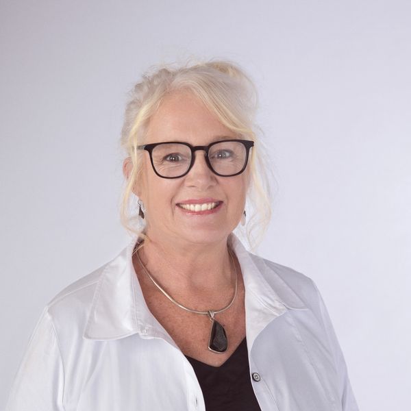 Smiling woman with glasses and white shirt.