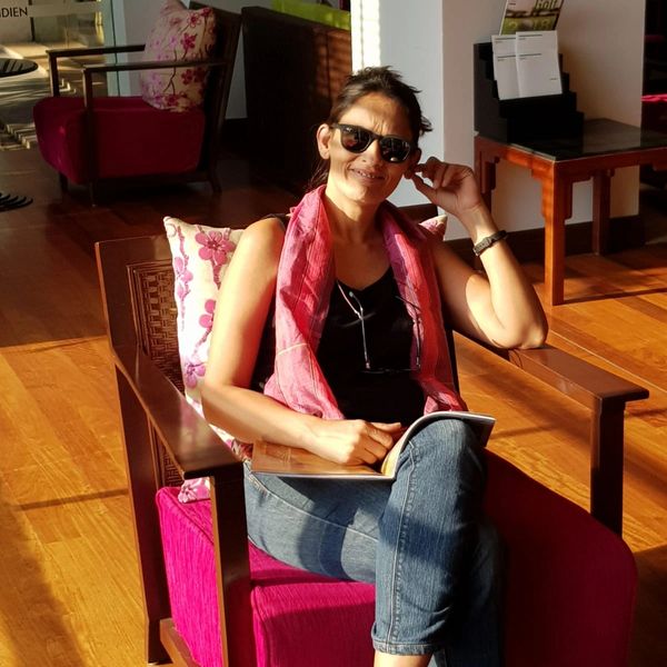 Woman sitting on a chair reading a book in sunlight.