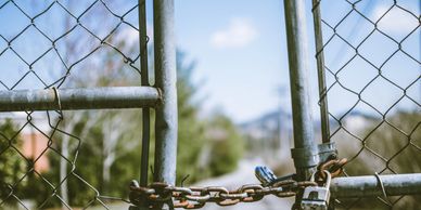 Photo by Travis Saylor (Pexels) of a padlock on a rusty chain link fence.