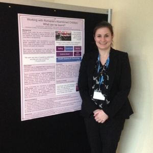 A trustee standing in front of a poster presentation at a conference