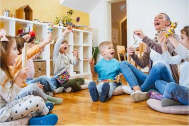 Children and teacher playing musical instruments in a circle indoors.