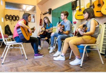 A guitar class with an instructor and three students practicing.