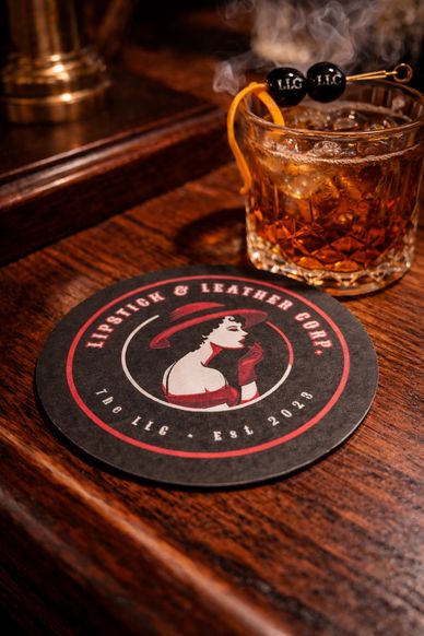 Elegant cocktail with branded coaster on wooden table.