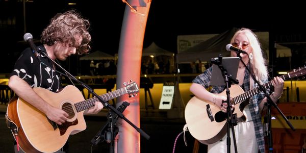 Two people playing acoustic guitars and singing.
