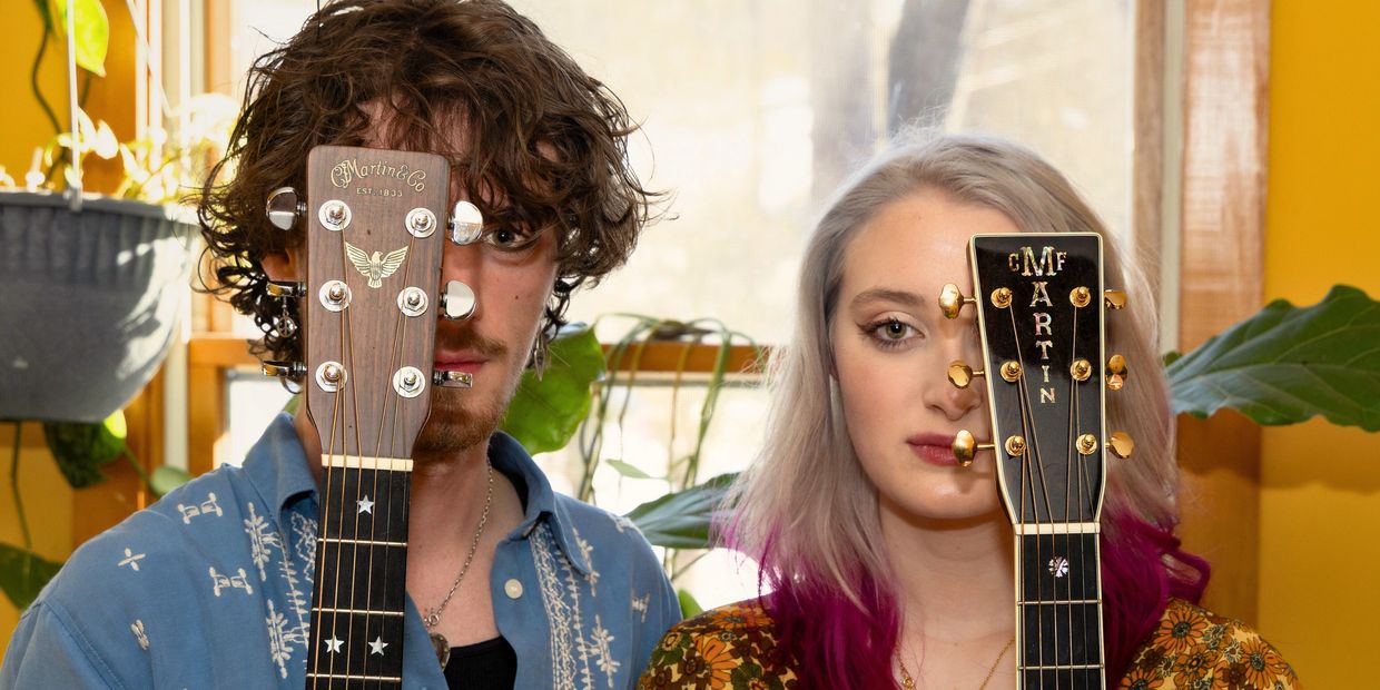 Two people holding guitars in front of their faces.