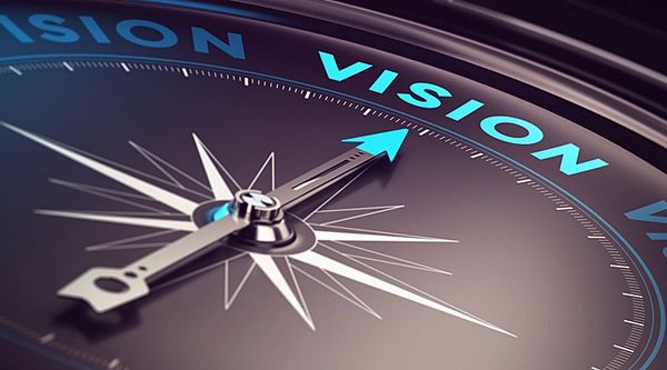 Close-up of a compass with the arrow pointing to the word 'VISION'.