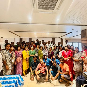 Large group of men and women posing indoors for a group photo.