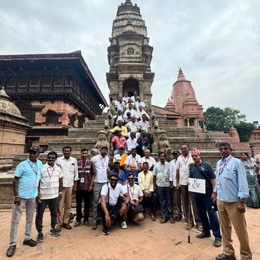 Large group photo in front of an ancient temple with intricate stone carvings.