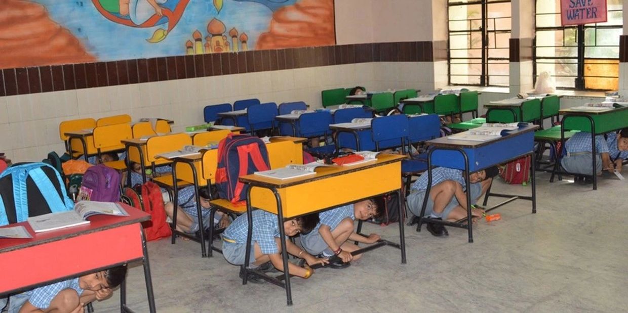 Children practicing drop cover hold to prevent injuries from falling objects during earthquake