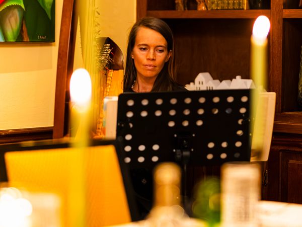 A woman focused on reading sheet music in a warmly lit room.