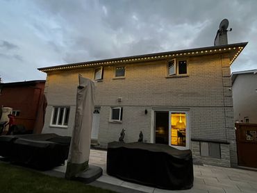 Permanent outdoor lights on a Markham two-storey home, softly illuminating the backyard patio area.