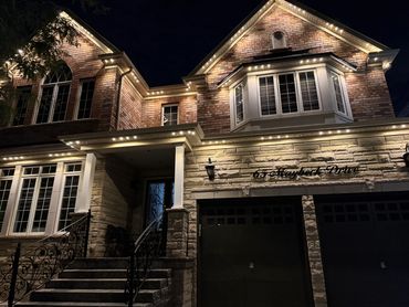 Permanent outdoor LED lights on a Woodbridge home highlighting stone façade and garage entrance.