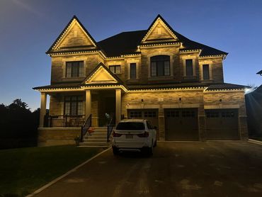 A two-story brick house in Vaughan illuminated with warm outdoor LED soffit lighting at dusk.