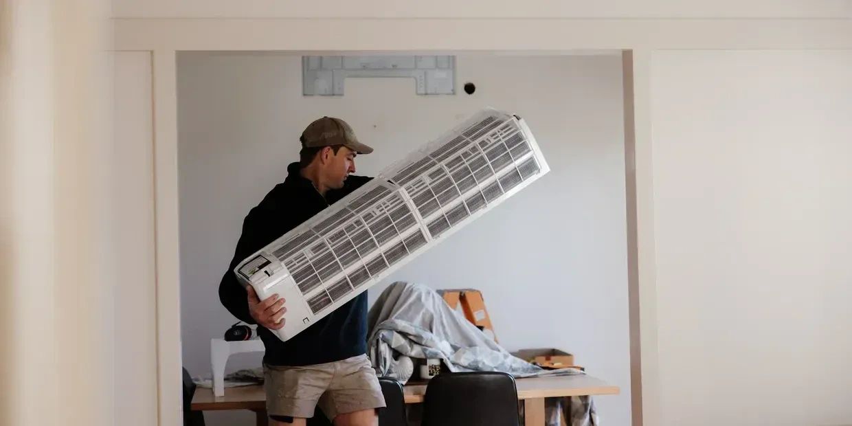 Man carrying an air conditioning unit indoors.