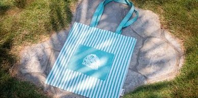 Striped canvas bag with surfing pelican logo—turquoise version shown; Souvenirs section color photo.